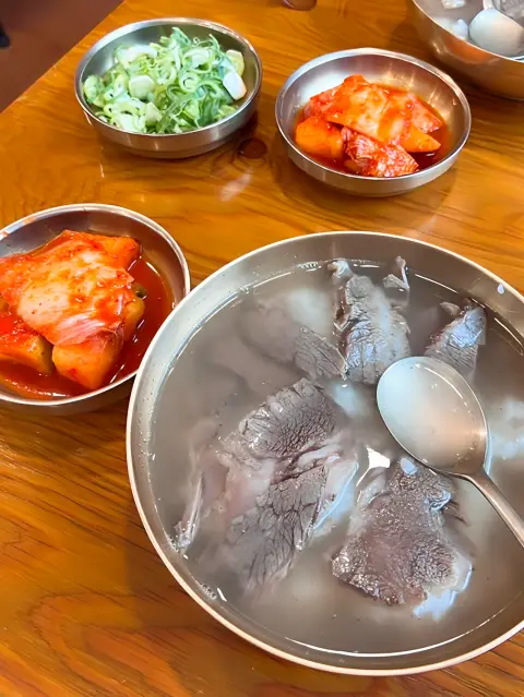 Hadongkwan gomtang served with kimchi and green onions on the side