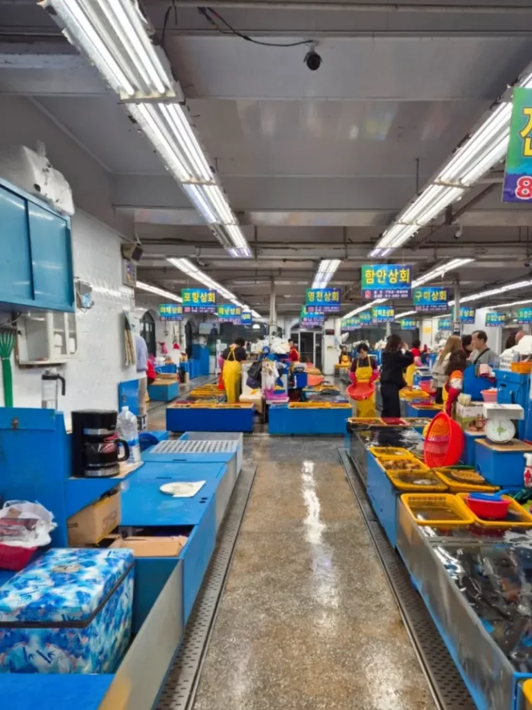 A wide aisle inside a busy seafood market in Busan