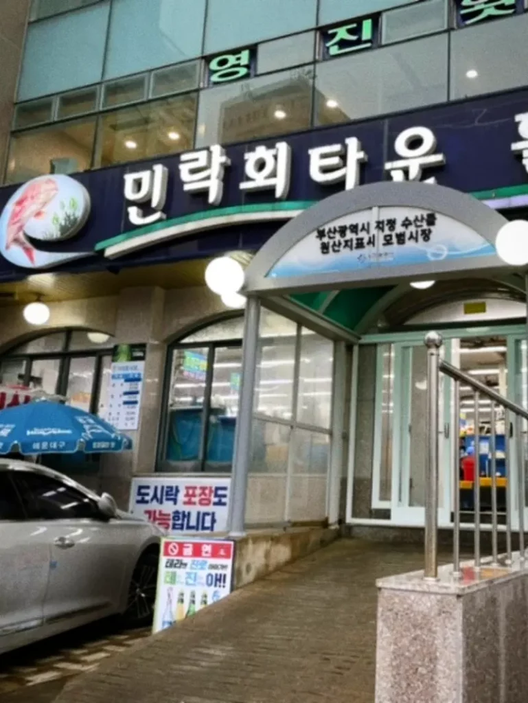 Entrance to Millak Raw Fish Center with signs and seafood banners
