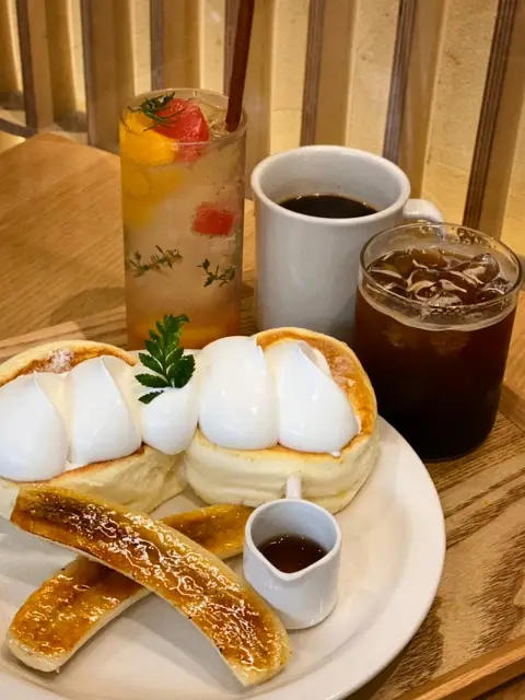 Soufflé pancake set with banana, syrup, and colorful drinks at cafe onhwa ikseon