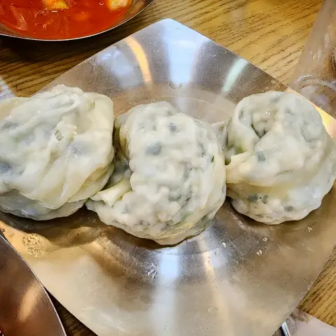 Handmade jjin-mandu served on a metal plate