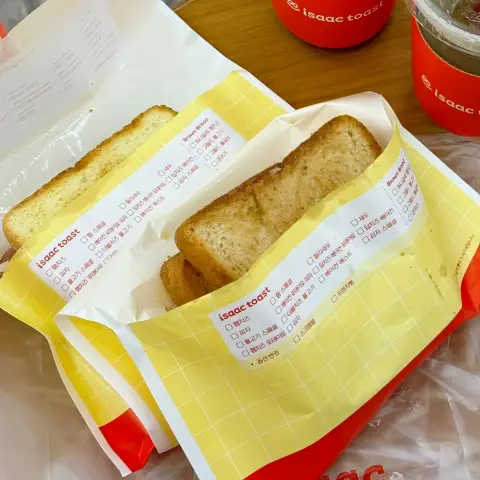 Two wrapped toasts and iced drinks in branded sleeves ready for takeout