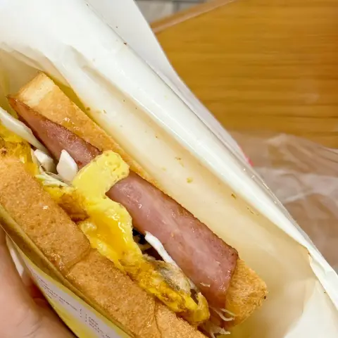 Isaac Toast Myeongdong handheld toast showing ham, egg, cheese, and cabbage inside