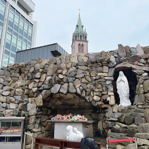 Isaac Toast Myeongdong near Myeongdong Cathedral grotto with statues and spire in the background