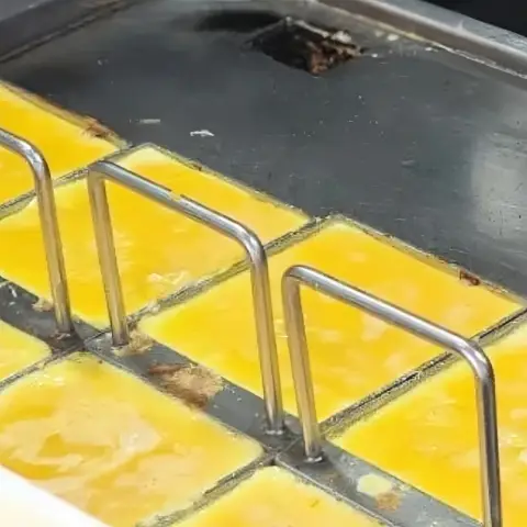 Egg squares cooking on a flat griddle with metal guides