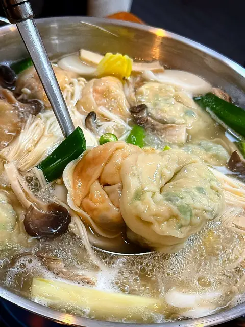 Gaeseong Mandu Koong dumpling hot pot with kimchi and pork mandu simmering in broth