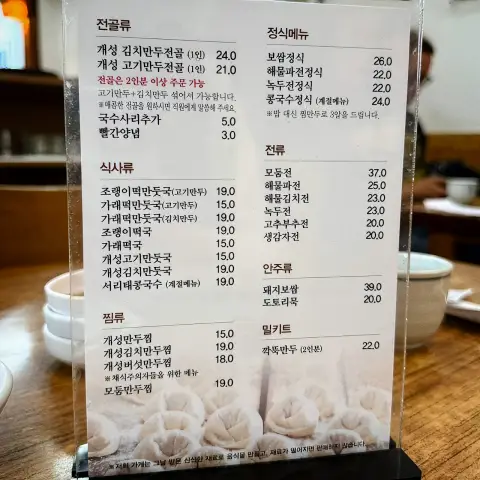 Restaurant menu board with various dumpling hot pot and side dish prices