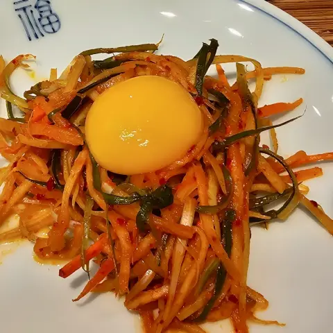 Green onion salad topped with raw egg yolk