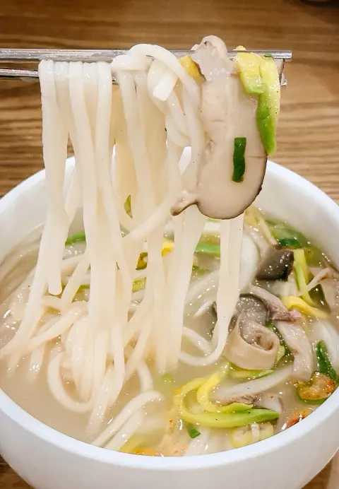 Steaming noodles lifted with chopsticks at Hwangsaengga Kalguksu