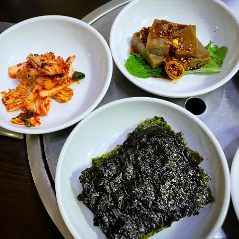 Assorted Korean side dishes including kimchi, acorn jelly, and seaweed