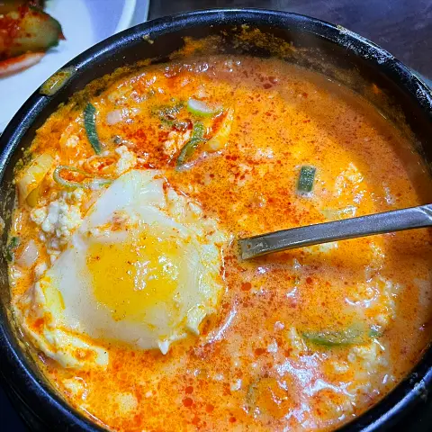 Jaedong Sundubu Seafood Sundubu with a perfectly poached raw egg floating in the spicy, red broth.