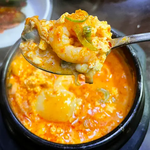 Fresh shrimp and soft tofu being served from the Jaedong Sundubu stew.